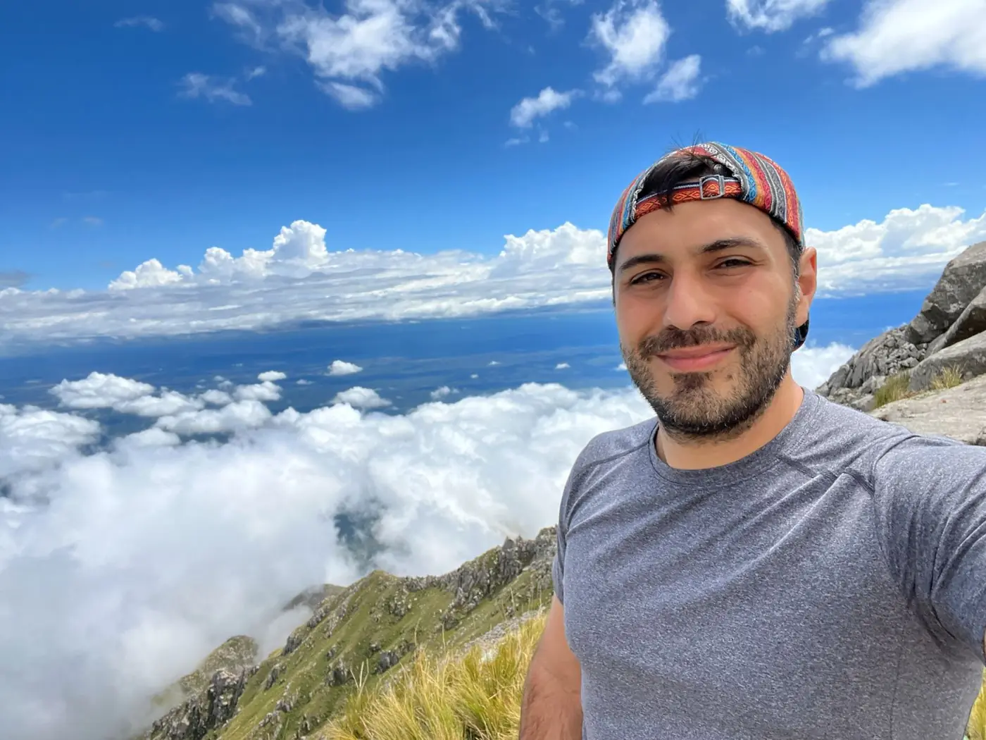Gabriel sonriendo en una cumbre por encima de un mar de nubes